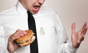 Angry Man holding hamburger with grease stain in his shirt
